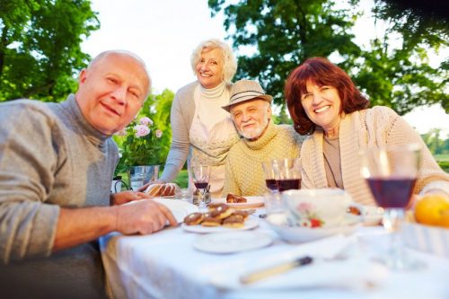 Glückliche Senioren am gedeckten Kaffeetisch Glückliche Senioren sitzen am gedeckten Kaffeetisch im Garten im Sommer