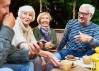 Ältere Freunde genießen die Zeit gemeinsam im Freien mit Kaffee, Gebäck und Tee